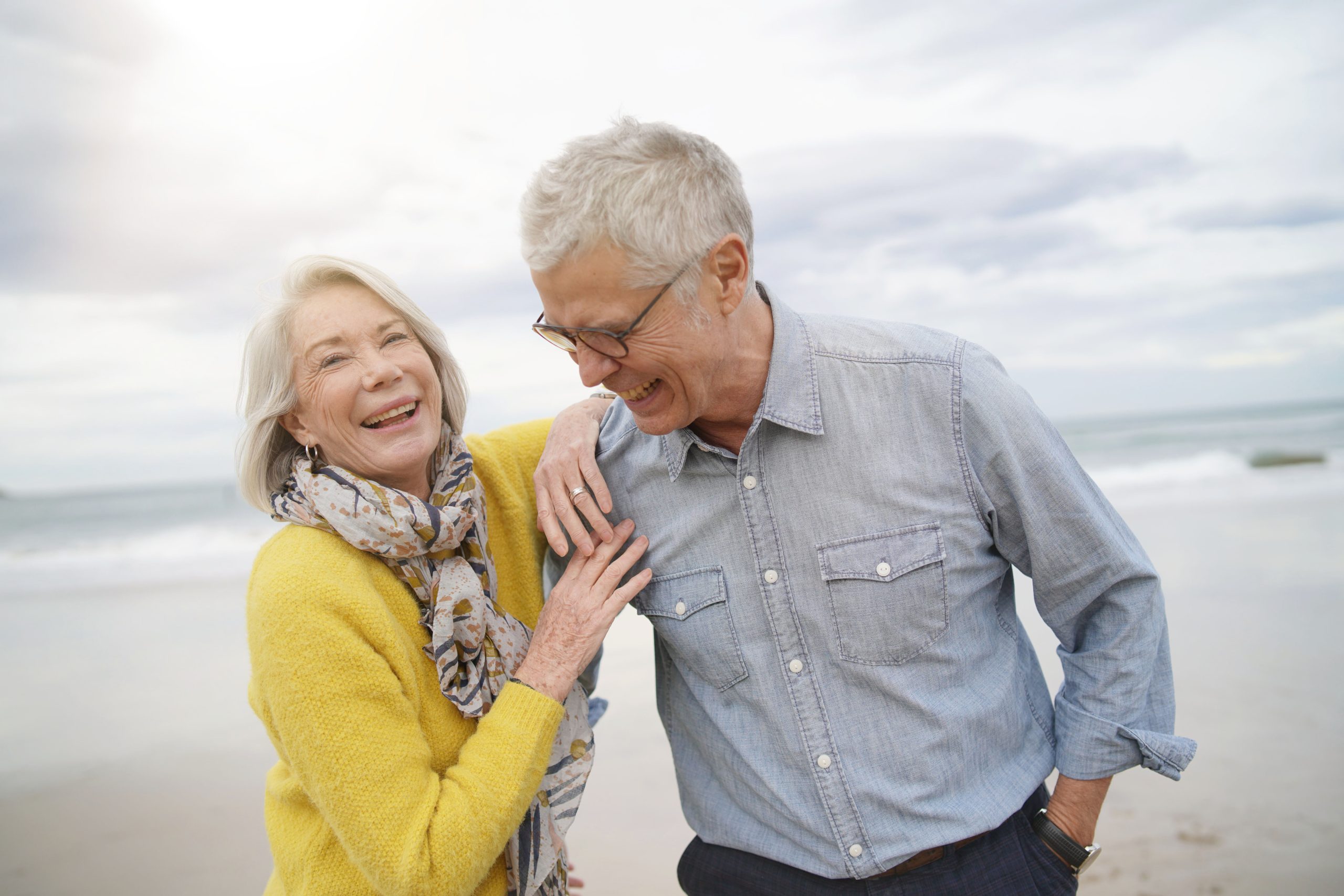 Portrait of happy modern senior couple on beach in fall